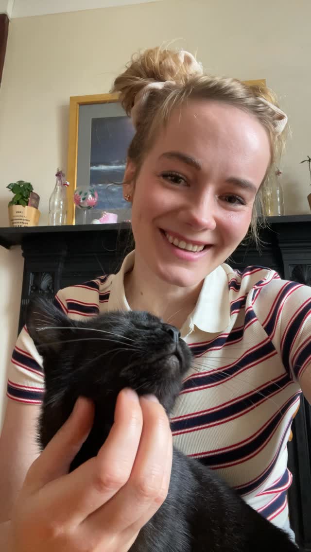 Me smiling with Yin, my black cat, in my arms.